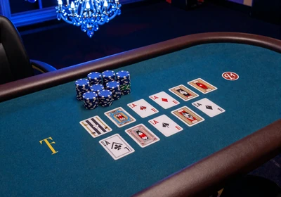 Poker-Tisch mit Community Cards und blauem Chip-Stapel im Casea Live Casino