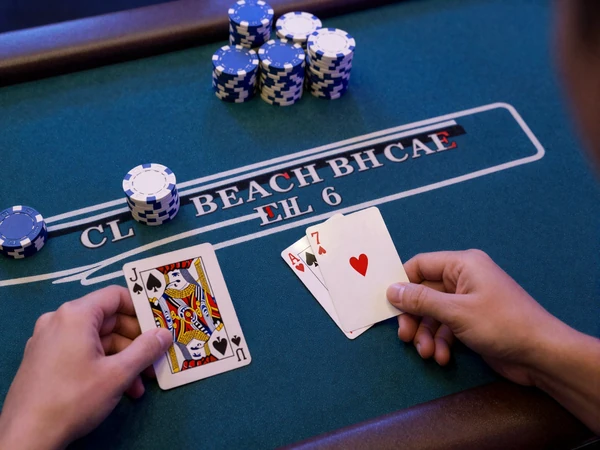Blackjack Hand von oben: Dealer zeigt 7, Spieler h&auml;lt Jack und 6 auf blauem Casea Tisch